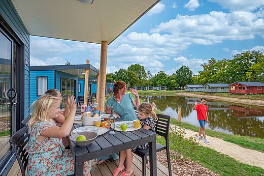 Familia en terraza de Mobil-home junto al lago en camping CAPFUN Vlinderloo.