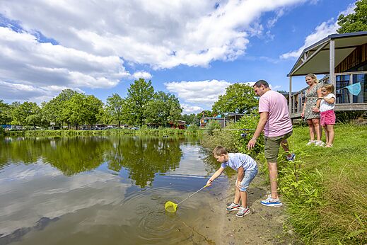Familia pescando con red y caña en estanque del camping CAPFUN Vlinderloo en Enschede.