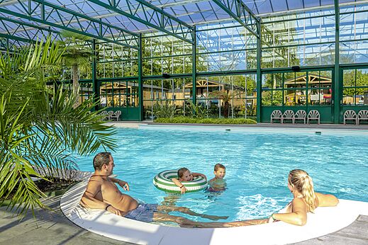Familia disfrutando de la piscina cubierta en el camping CAPFUN Vlinderloo en Enschede.