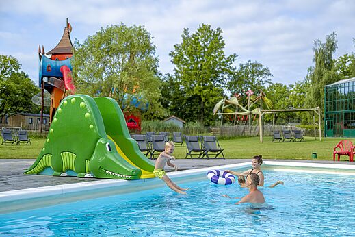 Niño en tobogán cocodrilo en la piscina exterior del camping CAPFUN Vlinderloo en Enschede.