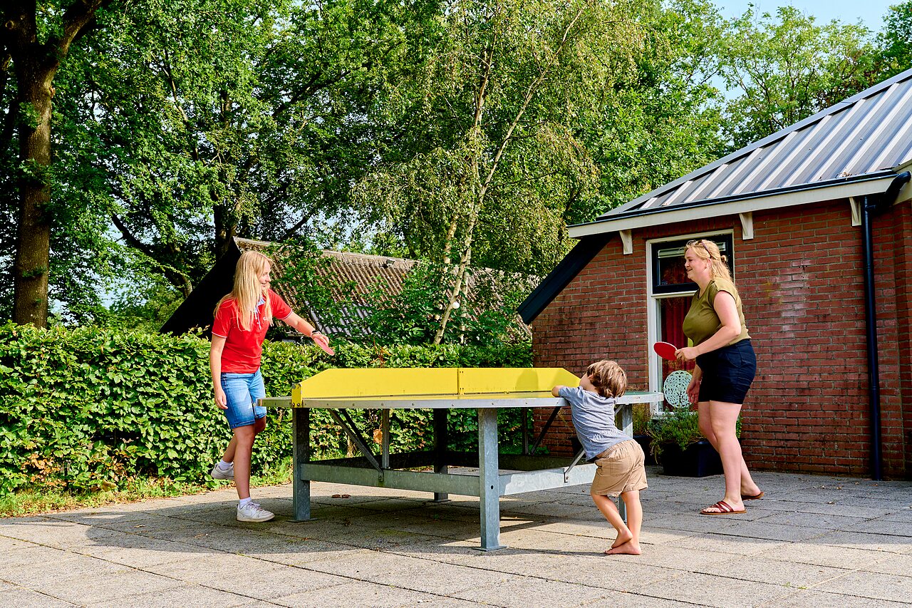 Familia jugando al tenis de mesa exterior en el camping CAPFUN De Waldsang en Bakkeveen.
