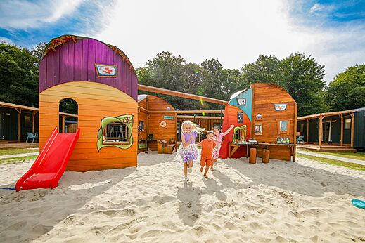 Niños jugando en un parque infantil con tobogán y arena en el camping CAPFUN De Waldsang a Bakkeveen.