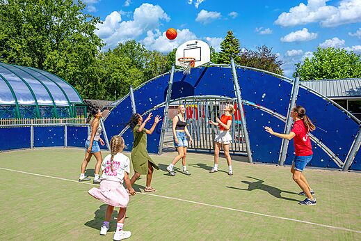 Jóvenes jugando baloncesto en una cancha multideporte en el camping CAPFUN De Waldsang en Bakkeveen.