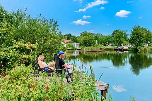 Pareja pescando y relajándose junto al agua en el camping CAPFUN De Waldsang en Bakkeveen.