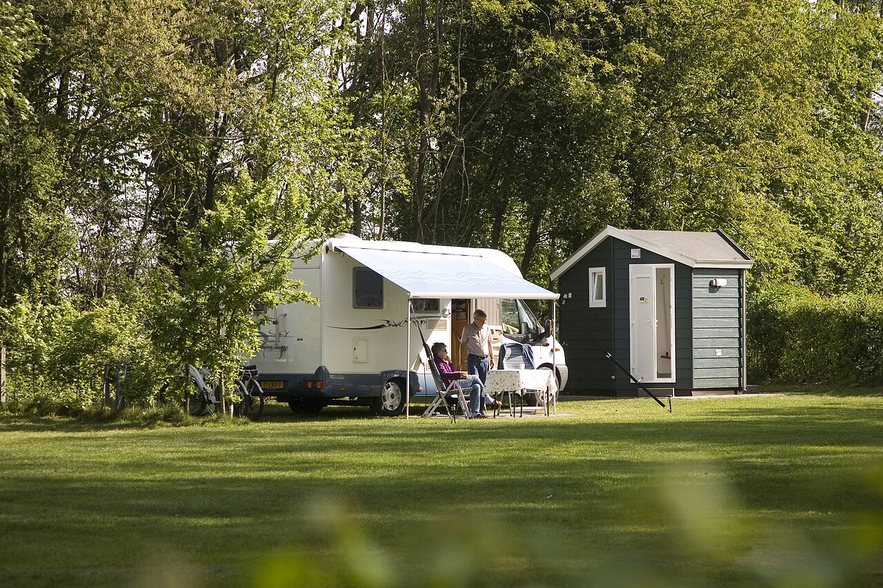 Parcela de camping con autocaravana, toldo y sanitarios privados en el camping CAPFUN Wieskamp en Winterswijk Henxel.