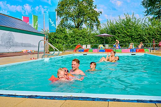 Familia y niños divirtiéndose en la piscina exterior en el camping CAPFUN Wieskamp en Winterswijk Henxel.