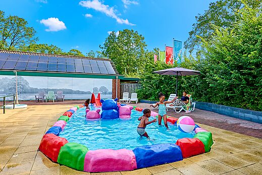 Piscina infantil colorida con niños y juegos acuáticos al camping CAPFUN Wieskamp.