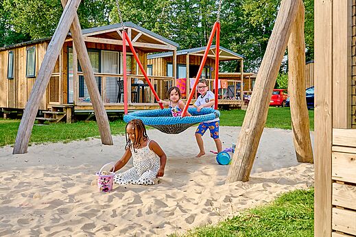 Columpio, arena y niños jugando en el camping CAPFUN Wieskamp en Winterswijk Henxel.