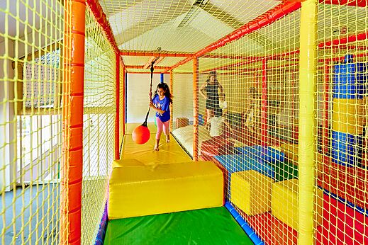 Zona de juegos interior con niño y columpio en el camping CAPFUN Wieskamp en Winterswijk Henxel.