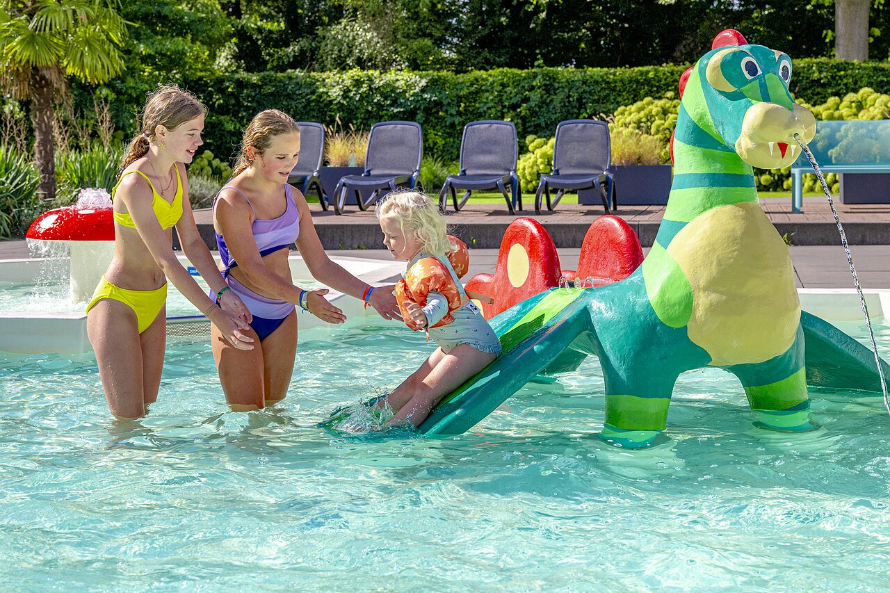 Ni�os jugando en piscina infantil con tobog�n dinosaurio en camping CAPFUN het Winkel en Winterswijk.