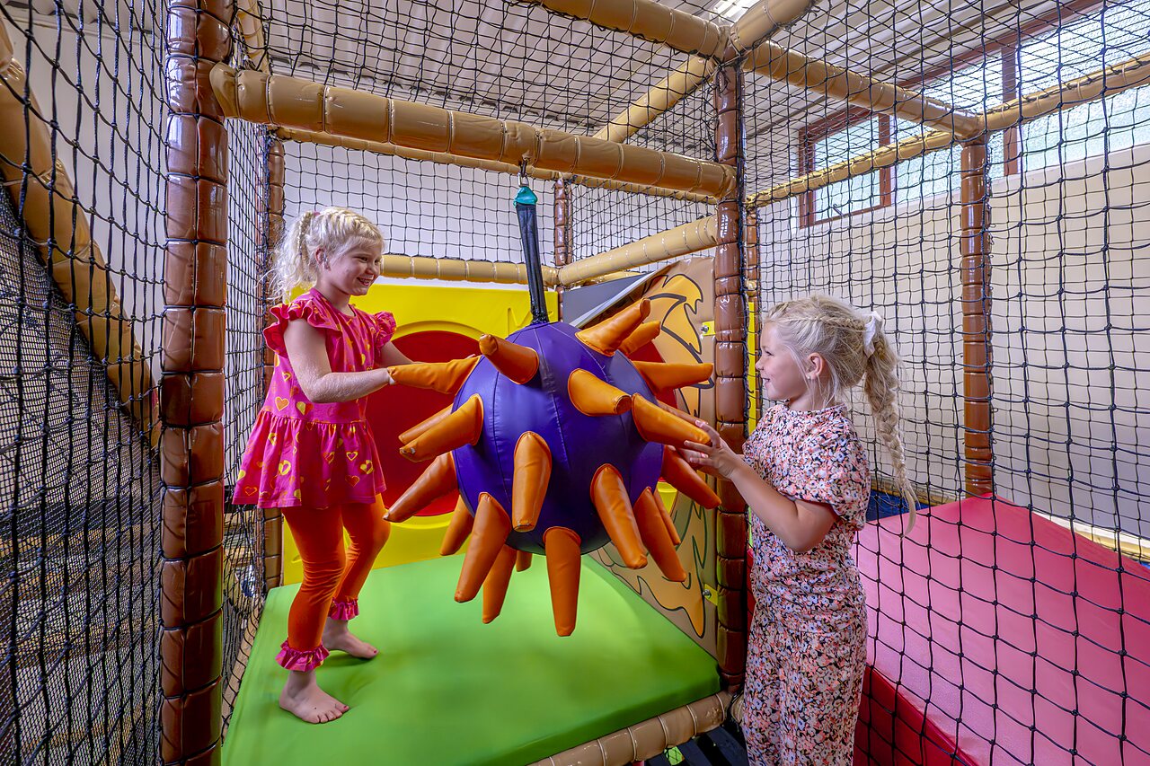 Dos ni�as jugando con un juego colgante en la zona de juegos interior del camping CAPFUN het Winkel en Winterswijk.