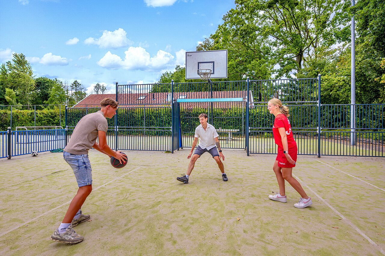 J�venes jugando baloncesto en la cancha multideportiva del camping CAPFUN het Winkel.