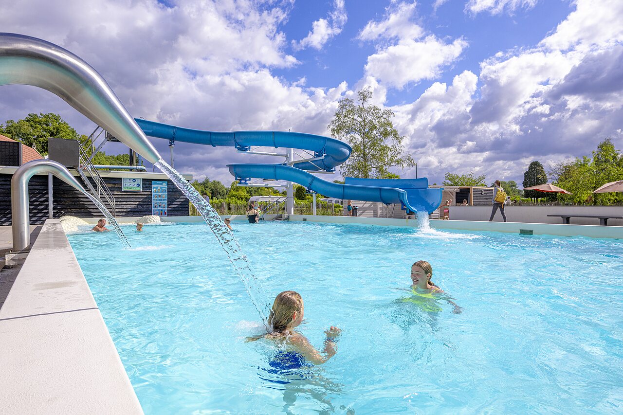 Piscina exterior con toboganes azules y chorros de agua en camping CAPFUN het Winkel, Winterswijk.