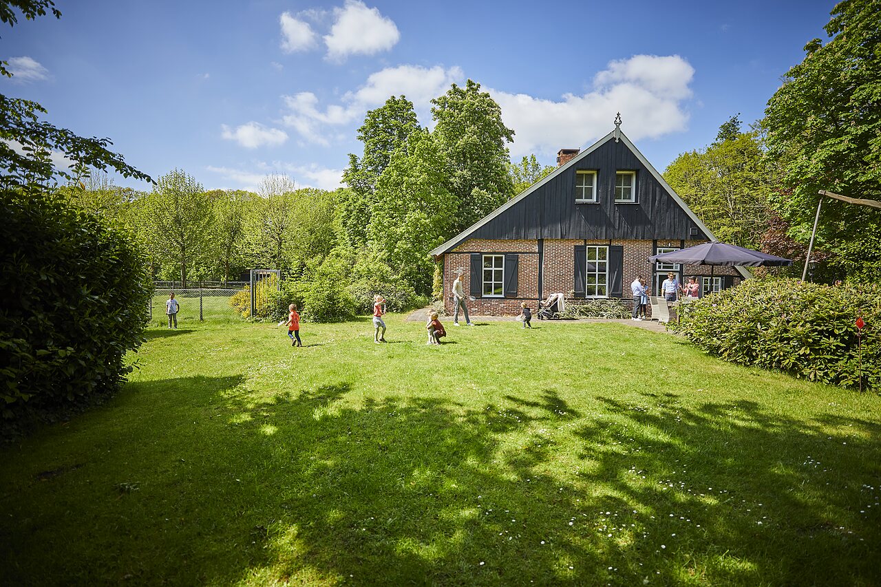 Ni�os jugando en el c�sped frente a edificio tradicional en camping CAPFUN het Winkel a Winterswijk.