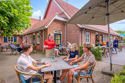 Terraza de restaurante exterior con camarera y clientes en el camping CAPFUN het Winkel en Winterswijk.