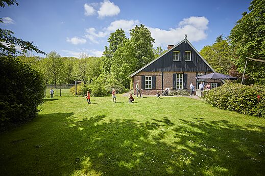 Restaurante con terraza exterior y ni�os jugando en el c�sped en el camping CAPFUN het Winkel en Winterswijk.