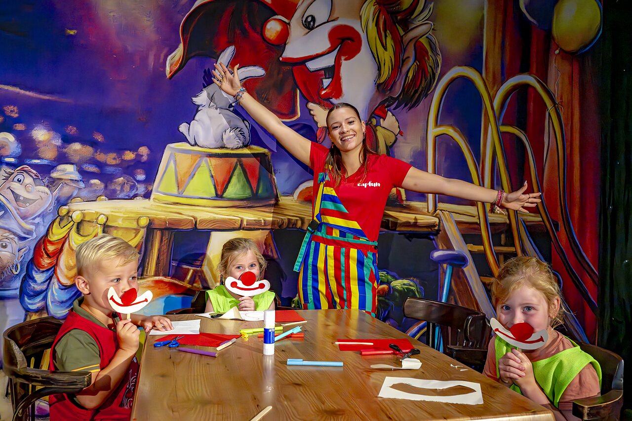 Ni�os creando m�scaras de payaso con la animadora en el camping CAPFUN de Wondermolen en Molenschot.