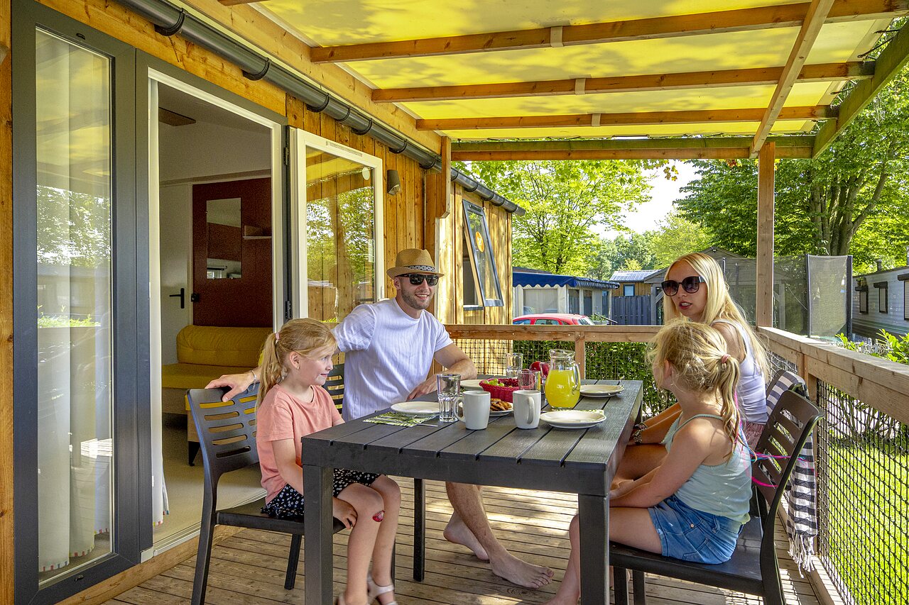 Familia desayunando en terraza de casa m�vil en camping CAPFUN de Wondermolen en Molenschot.