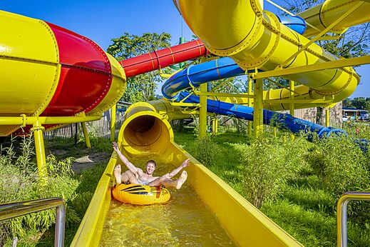 Hombre en flotador en tobogán acuático amarillo en el camping CAPFUN de Wondermolen en Molenschot.