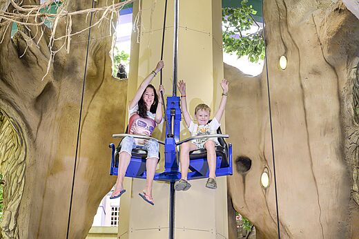 Madre e hijo sonriendo en una atracción de juegos interior en el camping CAPFUN de Wondermolen en Molenschot.