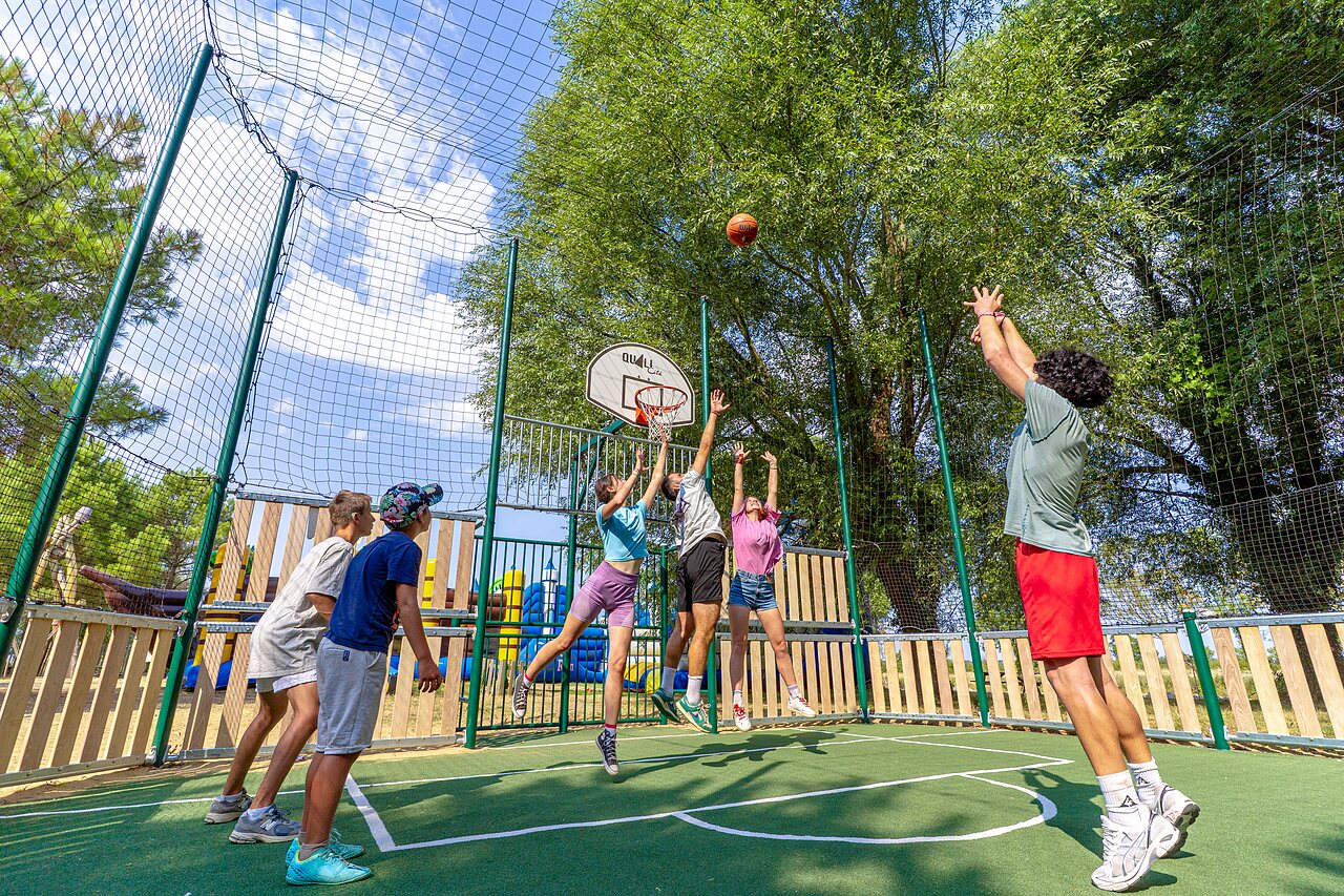 J�venes jugando baloncesto en cancha multideportiva en el camping CAPFUN Zagarella en LONGEVILLE SUR MER (85).