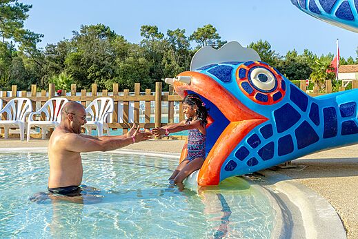 Niña bajando tobogán acuático de pez en la piscina del camping CAPFUN Zagarella en LONGEVILLE SUR MER (85).