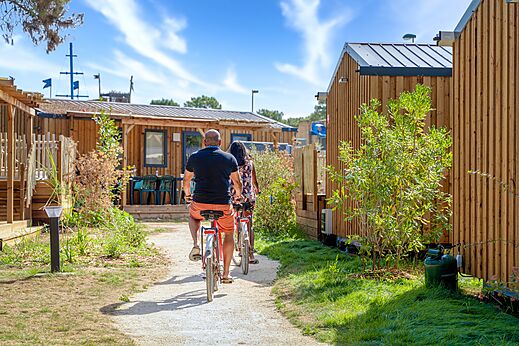 Pareja en bicicleta por un camino entre Mobil-homes en el camping CAPFUN Zagarella en LONGEVILLE SUR MER (85).