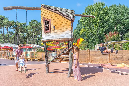 Zona de juegos con columpios y casita de madera en el camping CAPFUN Zephir en Les Mathes La Palmyre (17).