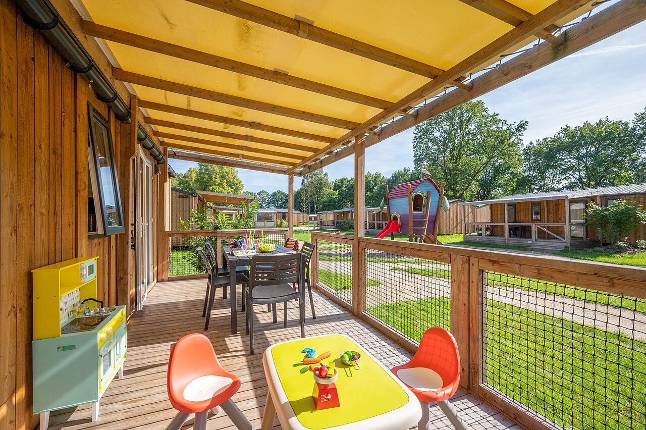 Terraza de Mobil-home con mesa de comedor y juegos infantiles en camping CAPFUN Zeumersehof en Voorthuizen.