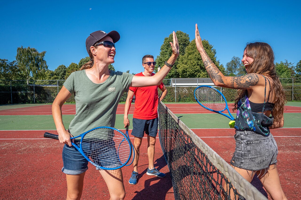 Jugadores de tenis sonrientes en la cancha multideporte del camping CAPFUN Zeumersehof en Voorthuizen.