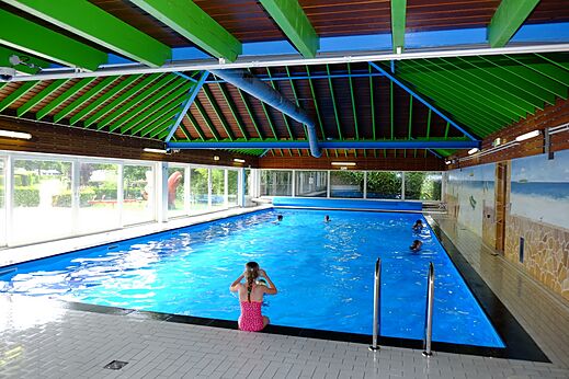 Piscina cubierta interior con bañistas en el camping CAPFUN Zeumersehof en Voorthuizen.