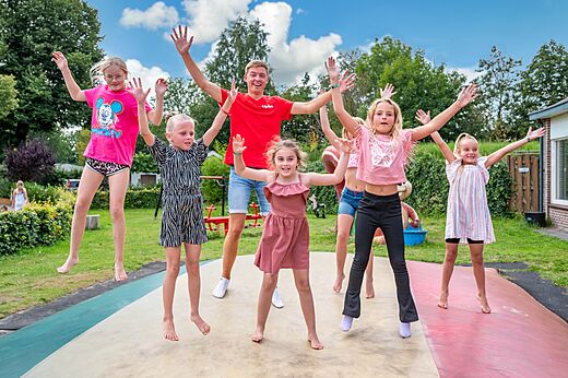 Niños y animador saltando en una cama elástica gigante en el camping CAPFUN Zeumersehof en Voorthuizen.