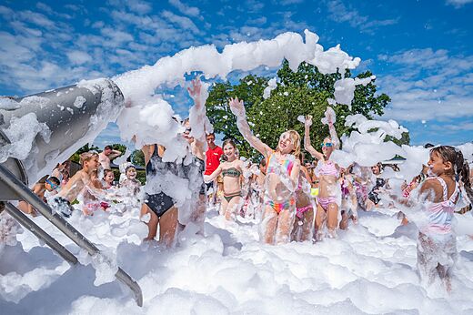 Niños felices jugando en la espuma con cañón de espuma en el camping CAPFUN Zeumersehof en Voorthuizen.