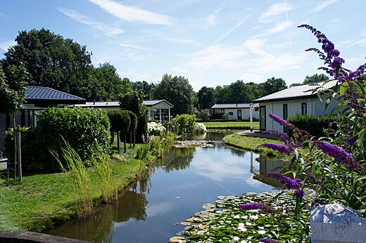 Modernos Mobil-homes junto a un canal florido en el camping CAPFUN Zeumersehof en Voorthuizen.