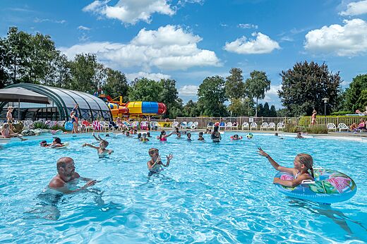 Piscina exterior con toboganes acuáticos y bañistas en el camping CAPFUN Zeumersehof en Voorthuizen.