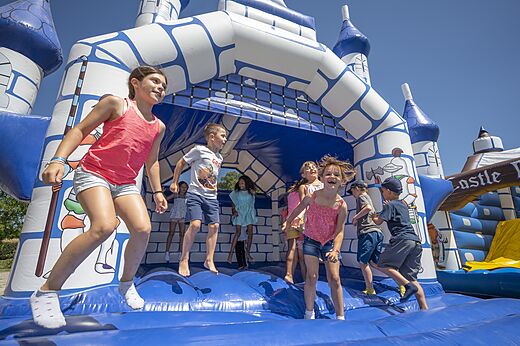 Niños saltando en un castillo hinchable azul y blanco en el camping CAPFUN Zeumersehof en Voorthuizen.